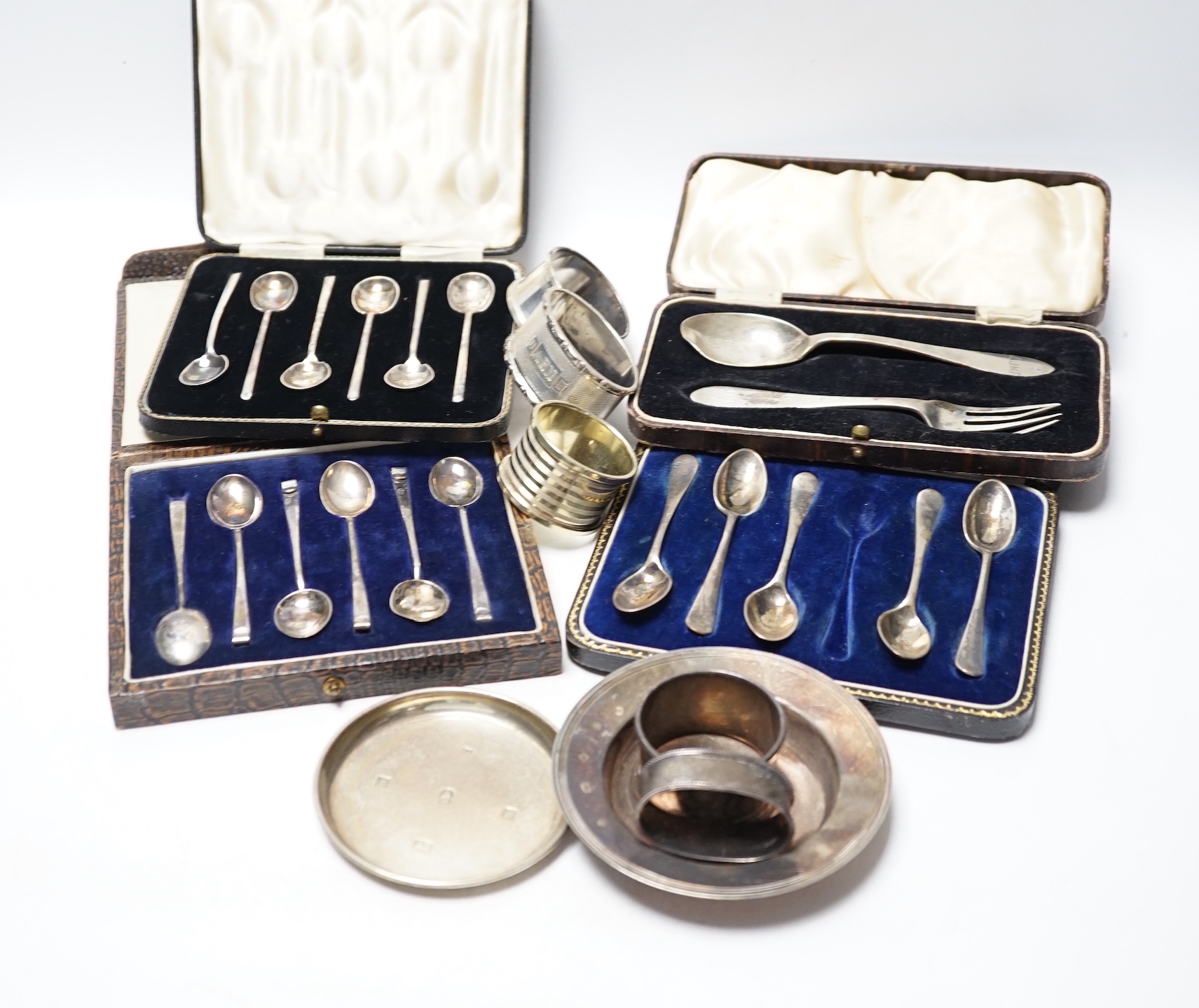 Four various silver serviette rings and a plated napkin ring, two small silver dishes, three various boxed sets of silver flatware and one part set of silver flatware.